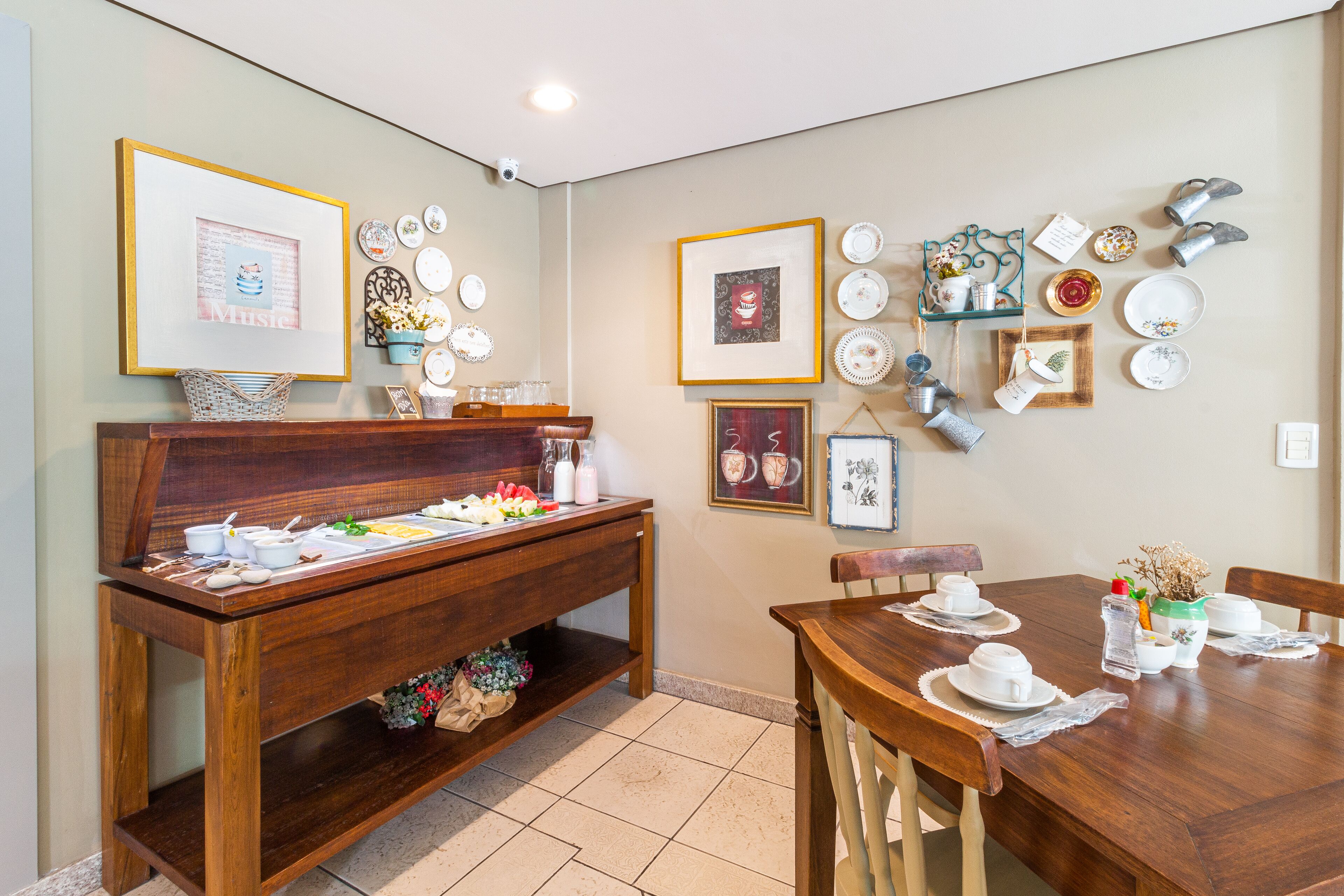 Un comedor con una mesa y sillas de madera, un aparador de madera con vajilla, y platos decorativos y cuadros colgados en la pared.