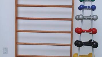 Exercise and relaxation space with a wall-mounted dumbbell rack, telephone, and storage options.