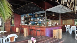 Een rustieke bar met houten meubels, een krijtbordmenu en diverse flessen en glazen.