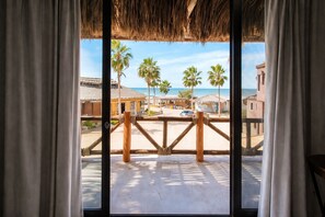 A balcony with a view of a beach, palm trees, and buildings. - Hotel Villas Mar y Arena (Comondu)