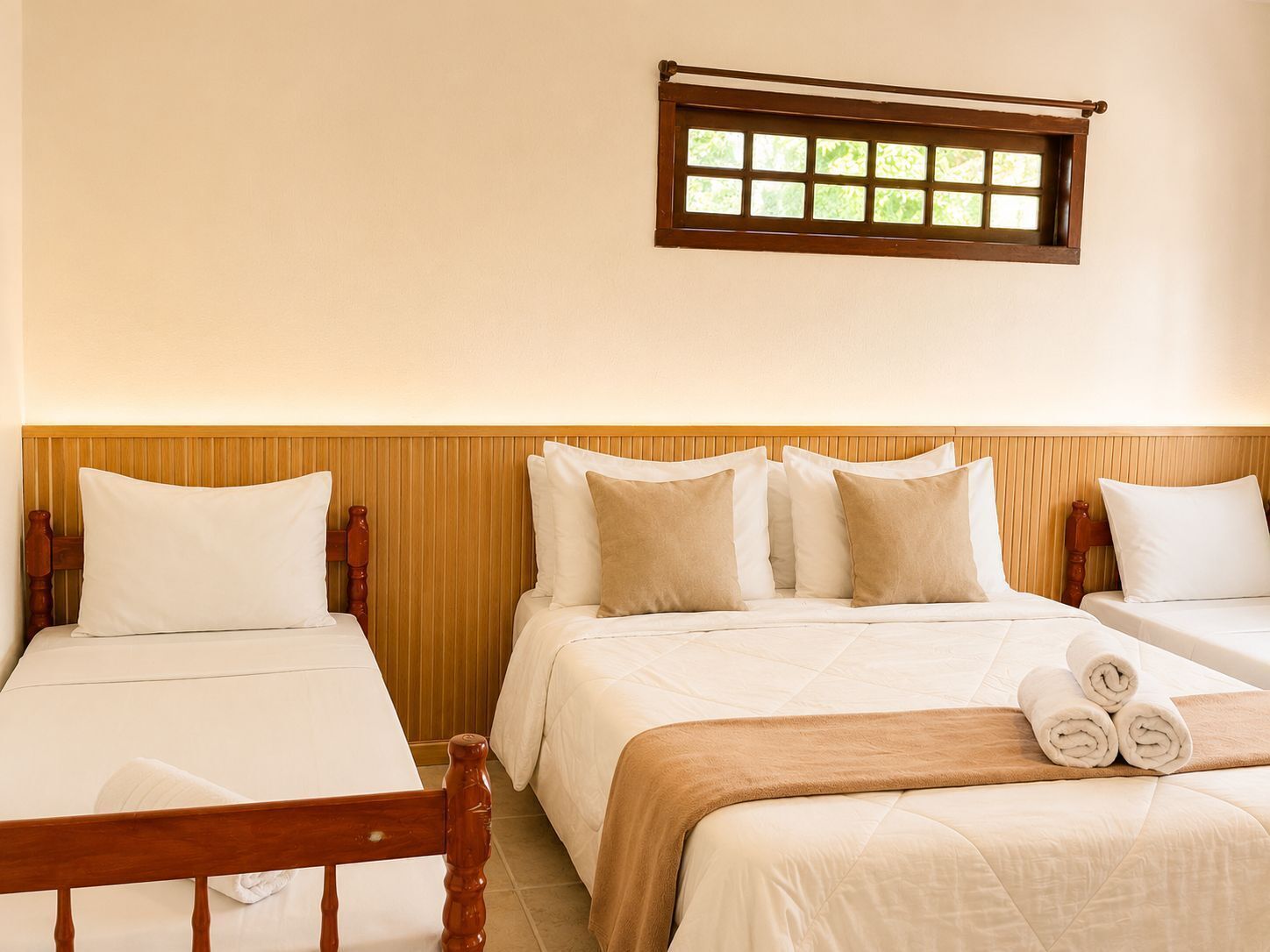 Une chambre d’hôtel avec deux lits, une tête de lit en bois, une fenêtre donnant sur un beau paysage et une serviette sur le lit.