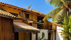 A swimming pool with blue tiles, surrounded by wicker chairs and a thatched roof structure. - EstrelaMar Ferradura Pousada, Restaurante & Spa (Búzios)