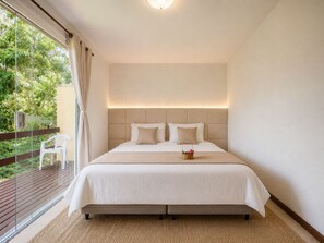 Une chambre à coucher avec un lit, une table de chevet, une fenêtre avec des rideaux et une vue sur la verdure à l’extérieur.