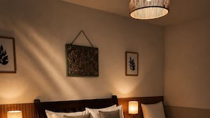 A hotel room with a large bed, two bedside tables with lamps, a hanging light fixture, and a decorative wall piece. - EstrelaMar Ferradura Pousada, Restaurante & Spa (Búzios)
