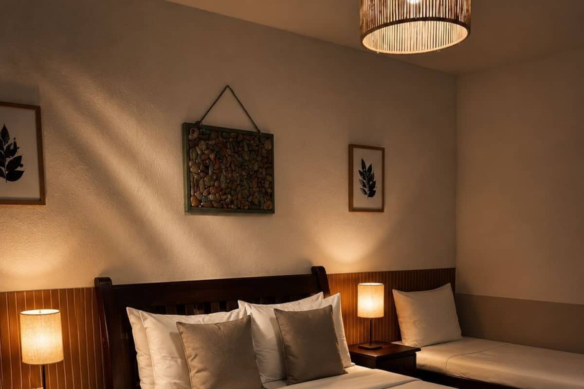 Une chambre d’hôtel avec un grand lit, deux tables de chevet avec des lampes, un luminaire suspendu et un élément décoratif mural.