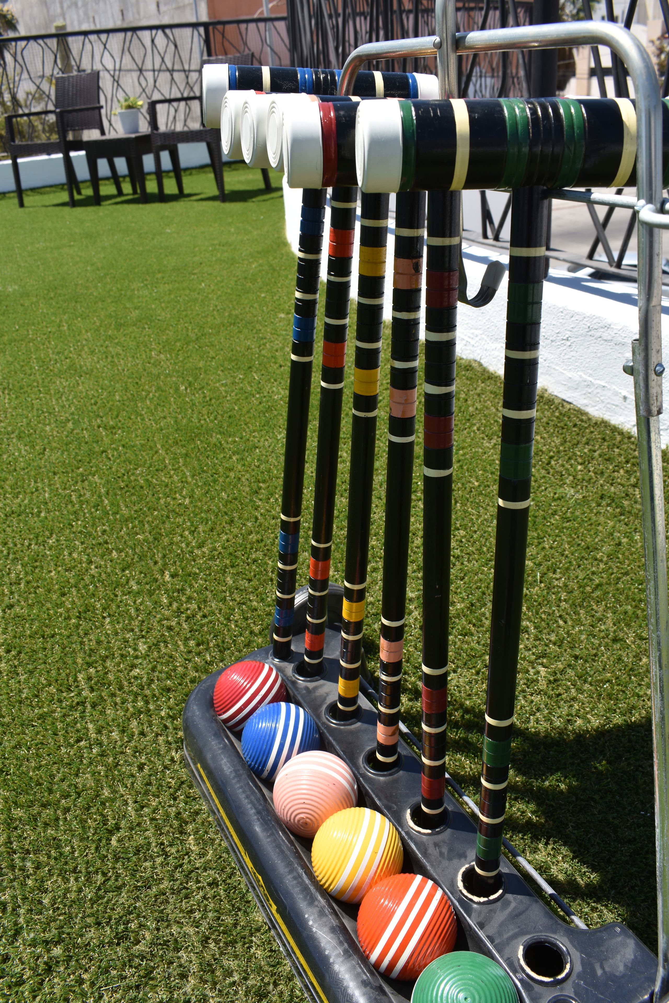 Un set da croquet su erba sintetica, con palline e mazze colorate.