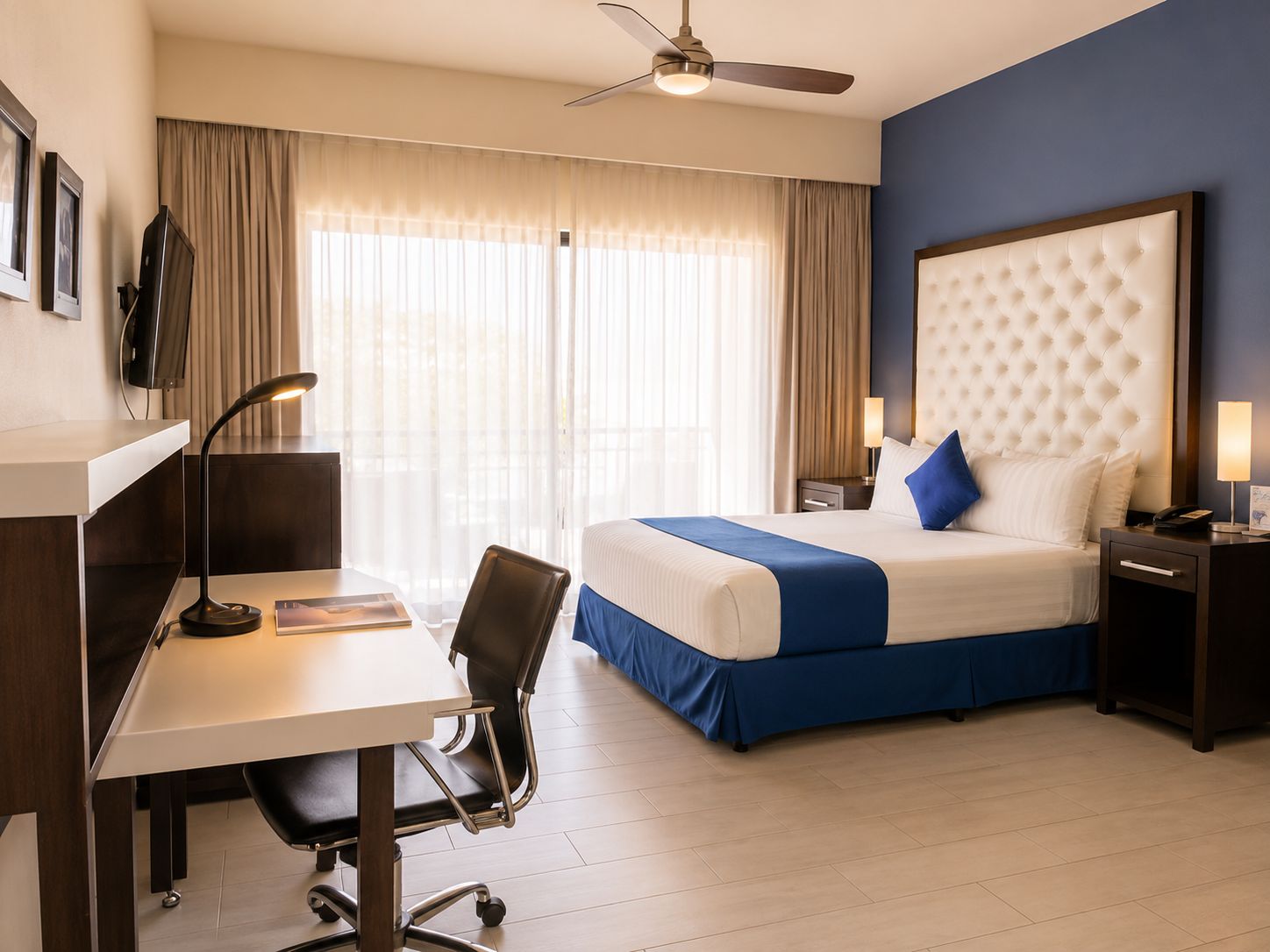 Une chambre d’hôtel équipée d’un lit, d’un bureau, d’une chaise et d’un ventilateur de plafond.