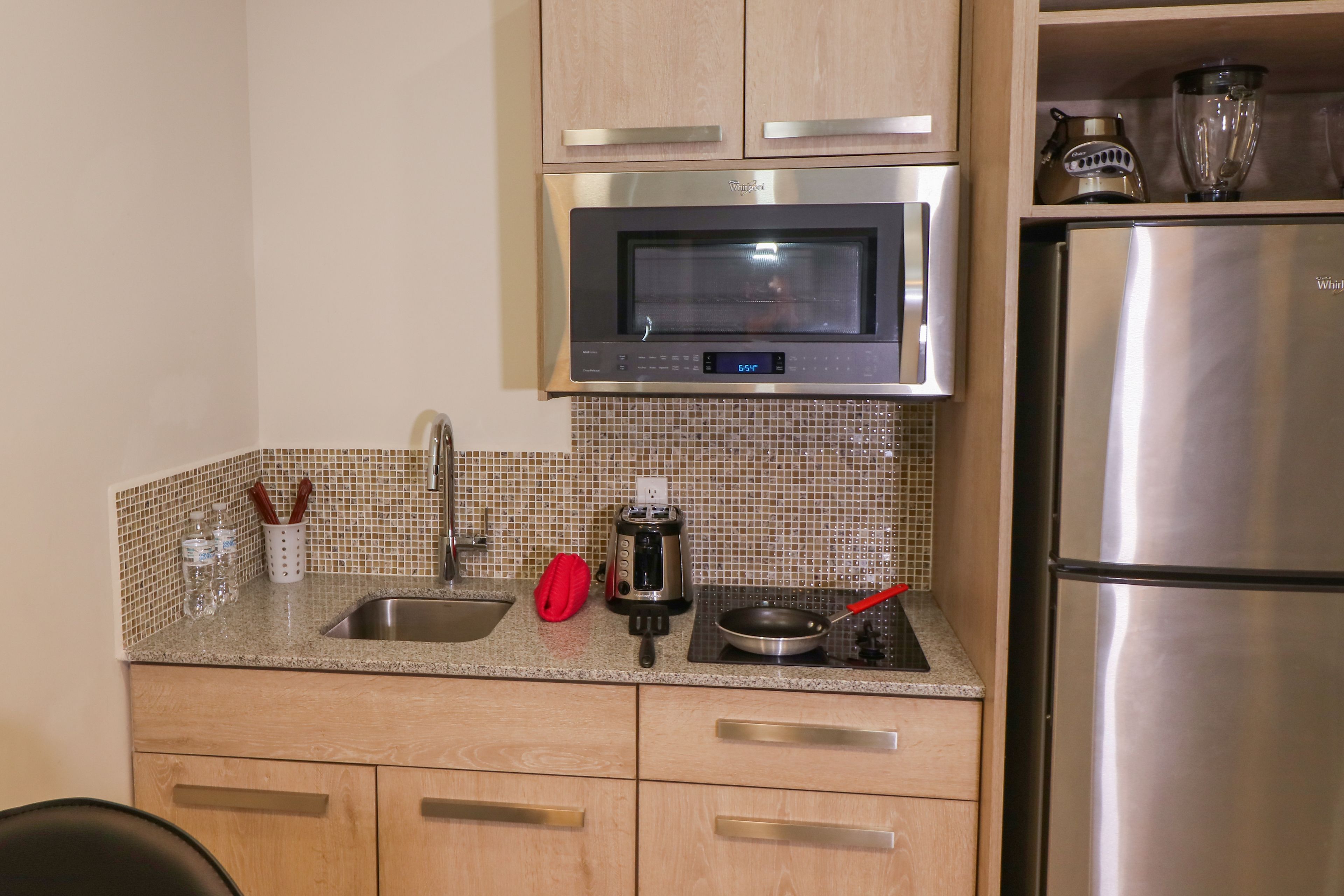 A kitchen with a stainless steel microwave, toaster, and refrigerator.
