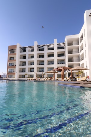 Una piscina al aire libre, sombrillas, sillones reclinables de piscina. Medano Hotel and Spa