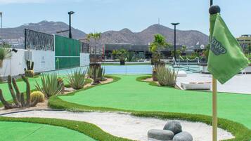A golf course with a flag, a pool, and mountains in the background.