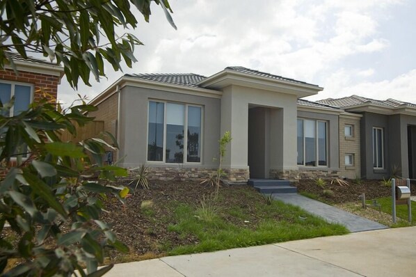 A modern two-story house with a stone foundation, large windows, and a well-maintained lawn. - Villa Saltwater (POINT COOK)