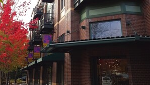 A multi-story building with brick facades, green awnings, and balconies. - Orenco Lofts (Hillsboro)