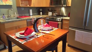A kitchen with a granite countertop, stainless steel appliances, and a dining table set with red napkins and plates. - Orenco Lofts (Hillsboro)