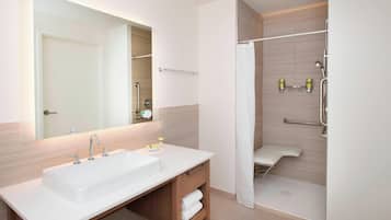 Un baño moderno con un lavamanos grande, espejo y ducha a ras de suelo.