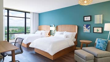 Une chambre d’hôtel avec deux lits, un bureau, une chaise et une vue sur la ville.