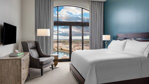 A hotel room with a large bed, a desk, a chair, a TV, and a view of a cityscape through a large window. - Element by Marriott Huntsville (Huntsville)
