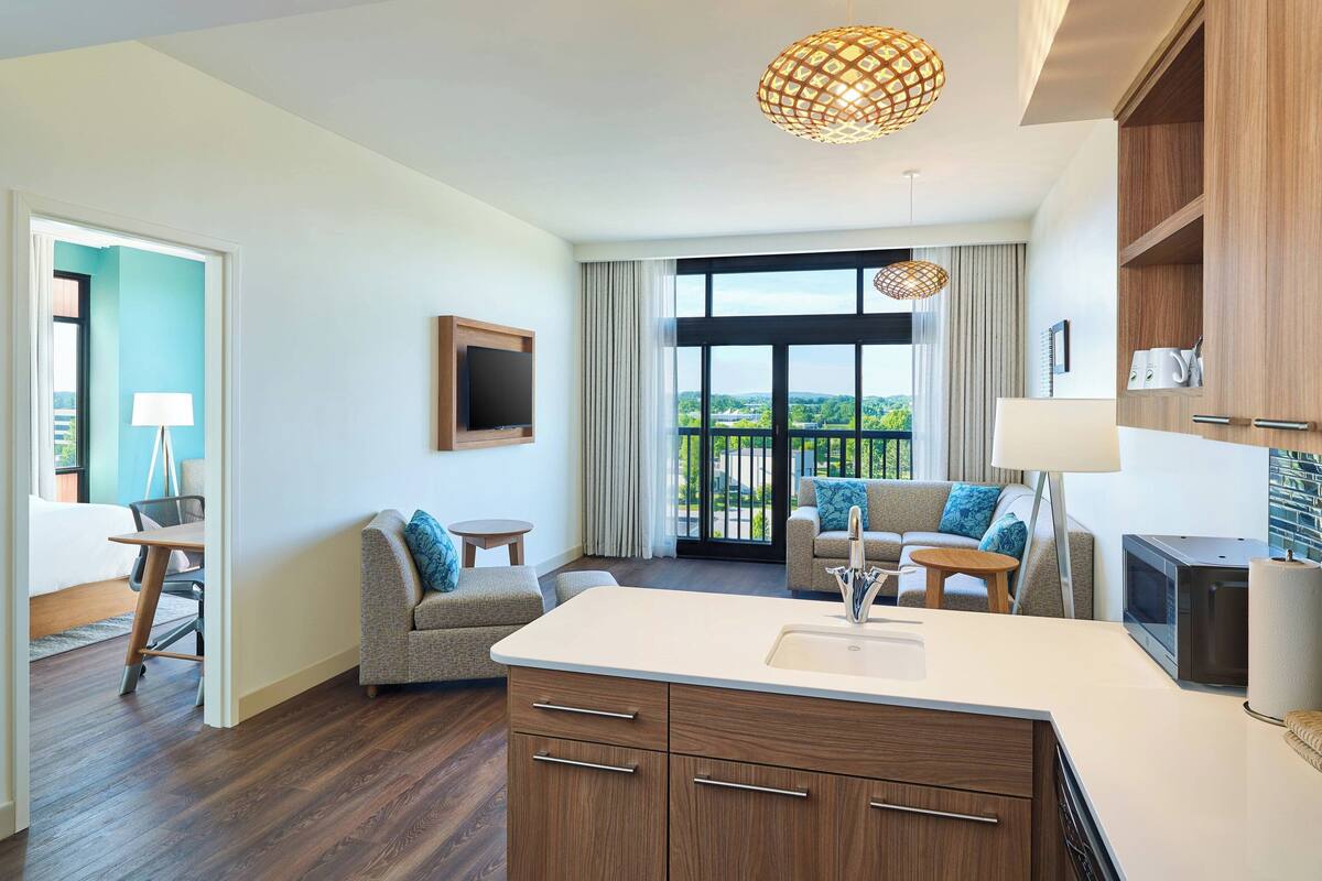 Une chambre d’hôtel moderne dotée d’un coin cuisine, d’un canapé, d’une table à manger et d’un balcon avec vue.