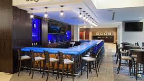 A bar area with a long counter, multiple bar stools, and a television screen. - Element by Marriott Huntsville (Huntsville)