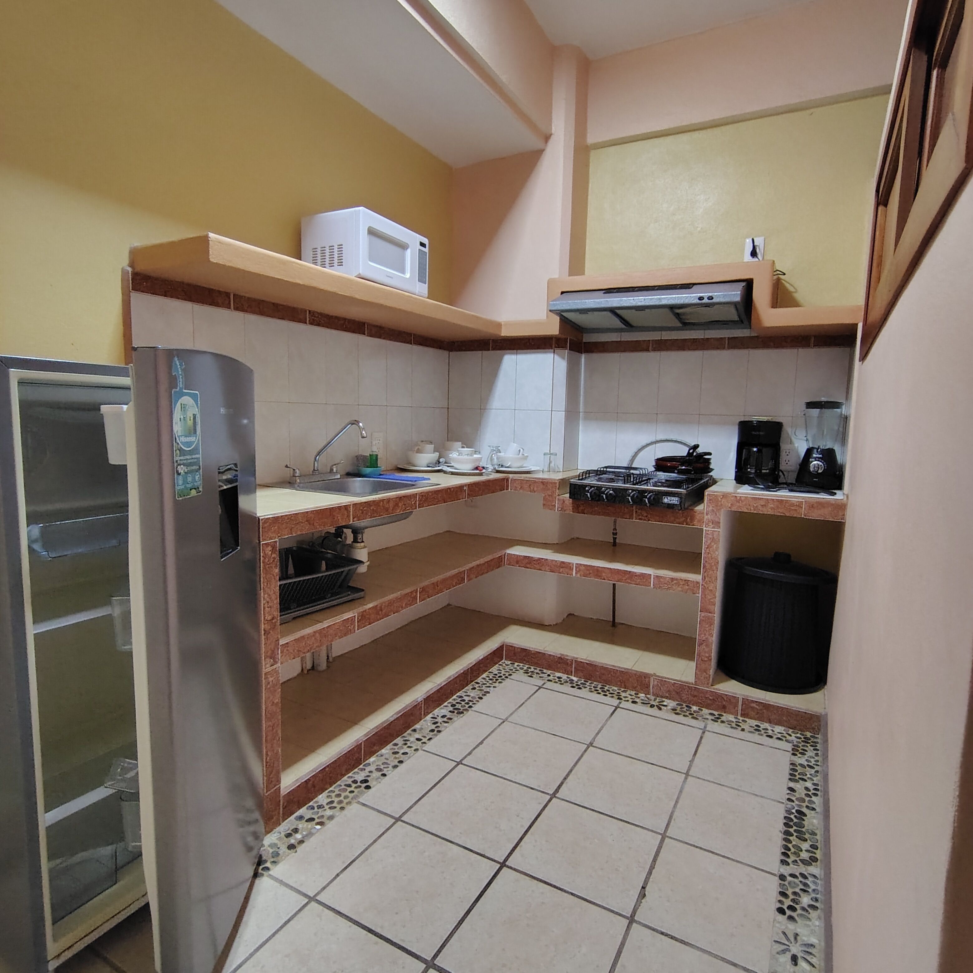 Een compacte keuken met een koelkast, magnetron, fornuis en spoelbak.