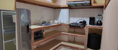 A compact kitchen with a refrigerator, microwave, stove, and sink.