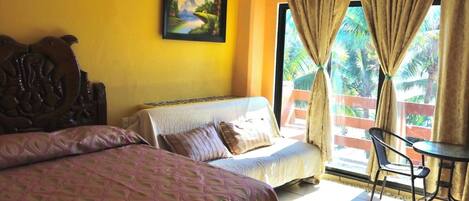 Una habitación con cama, sofá, mesa de comedor y ventana con cortinas.