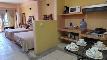 Habitación de hotel con dos camas, una kitchenette y un comedor con vajilla.