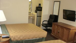 A hotel room with two beds, a desk, a chair, a television, and a cabinet.