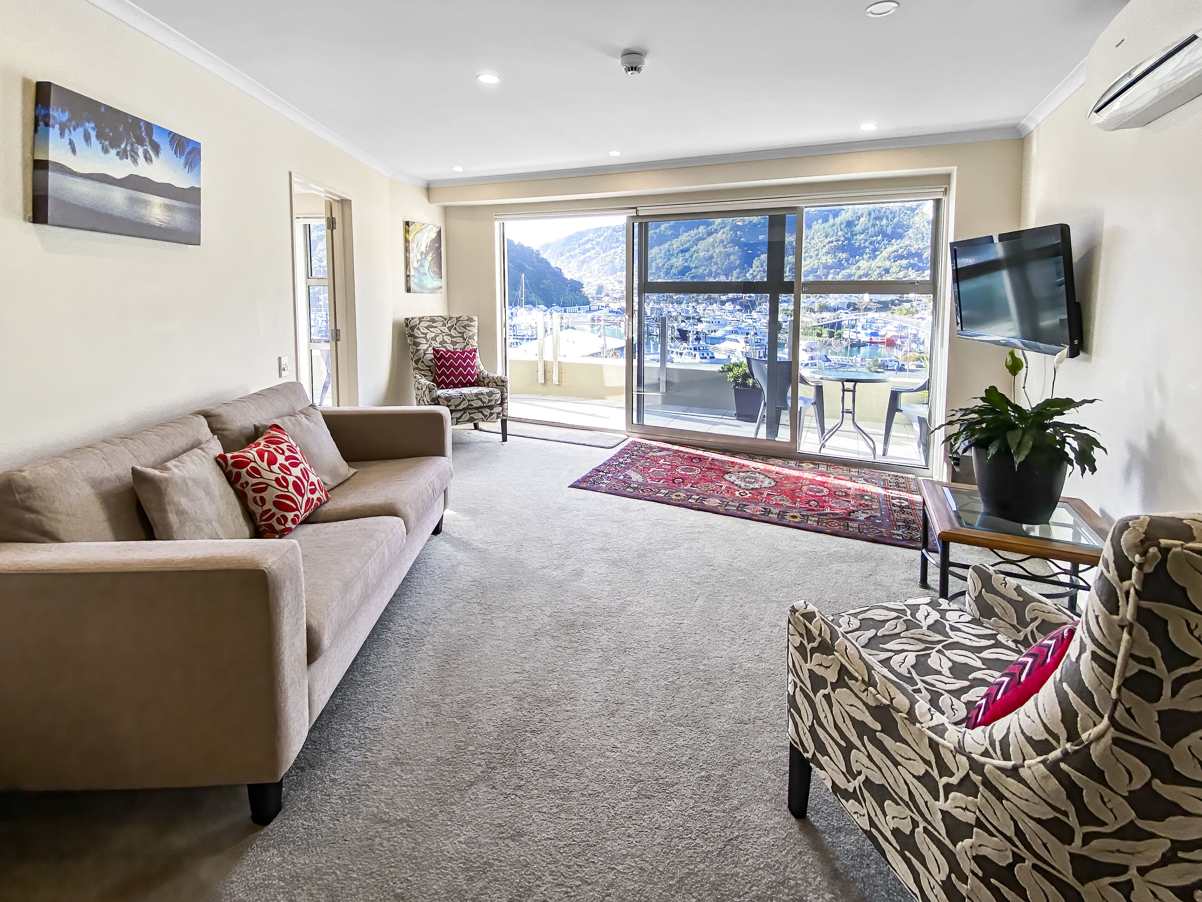 Una sala de estar con sofá, sillón y televisor sobre un mueble.