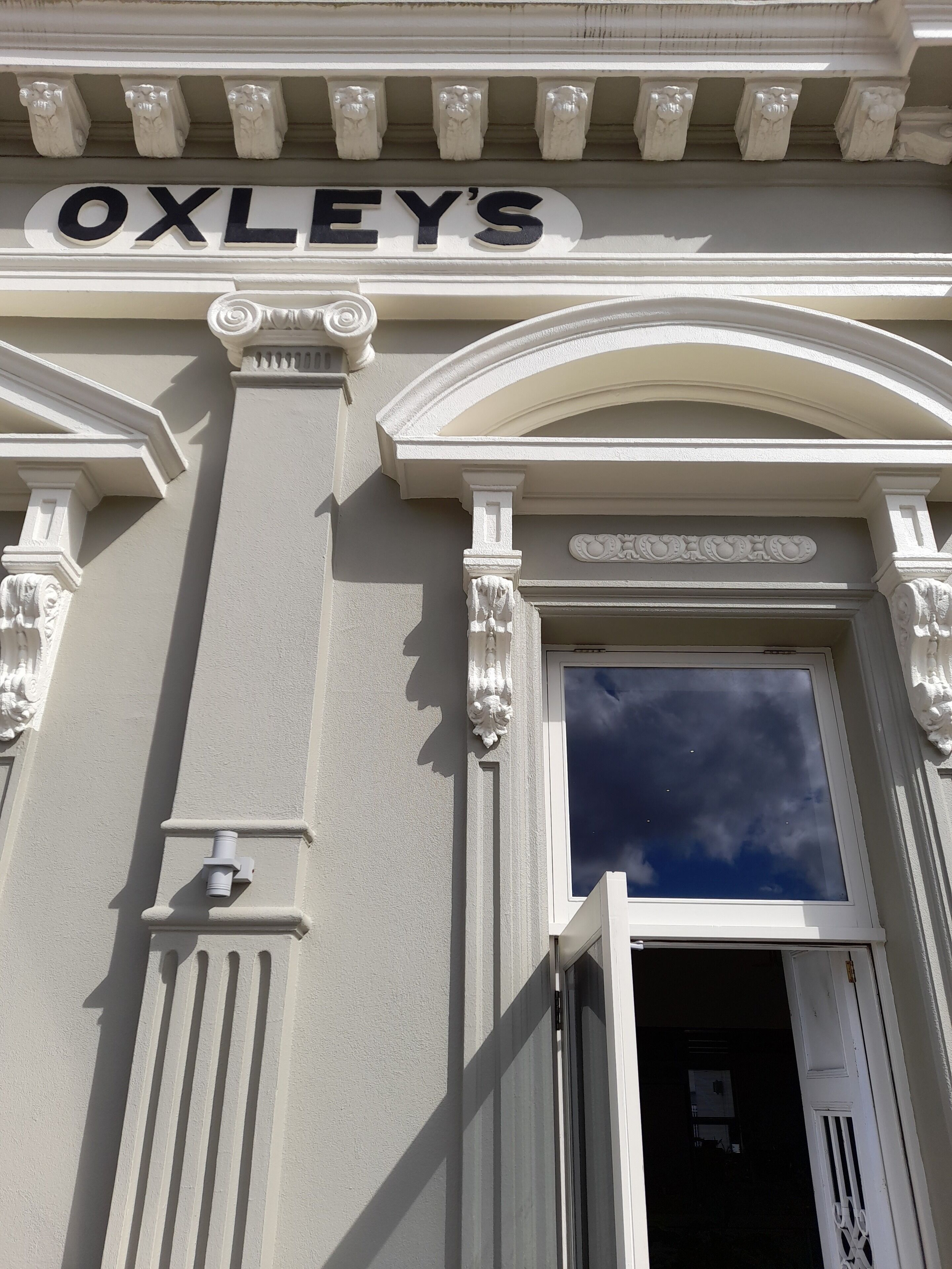 La façade d’un immeuble, avec une enseigne portant l’inscription « OXLEY’S » au-dessus d’une porte.