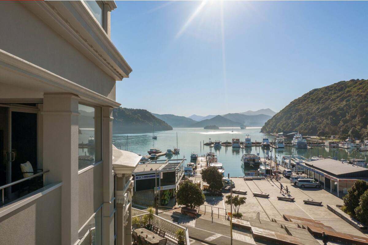 A balcony with a view of a marina, boats, and a hilly landscape.