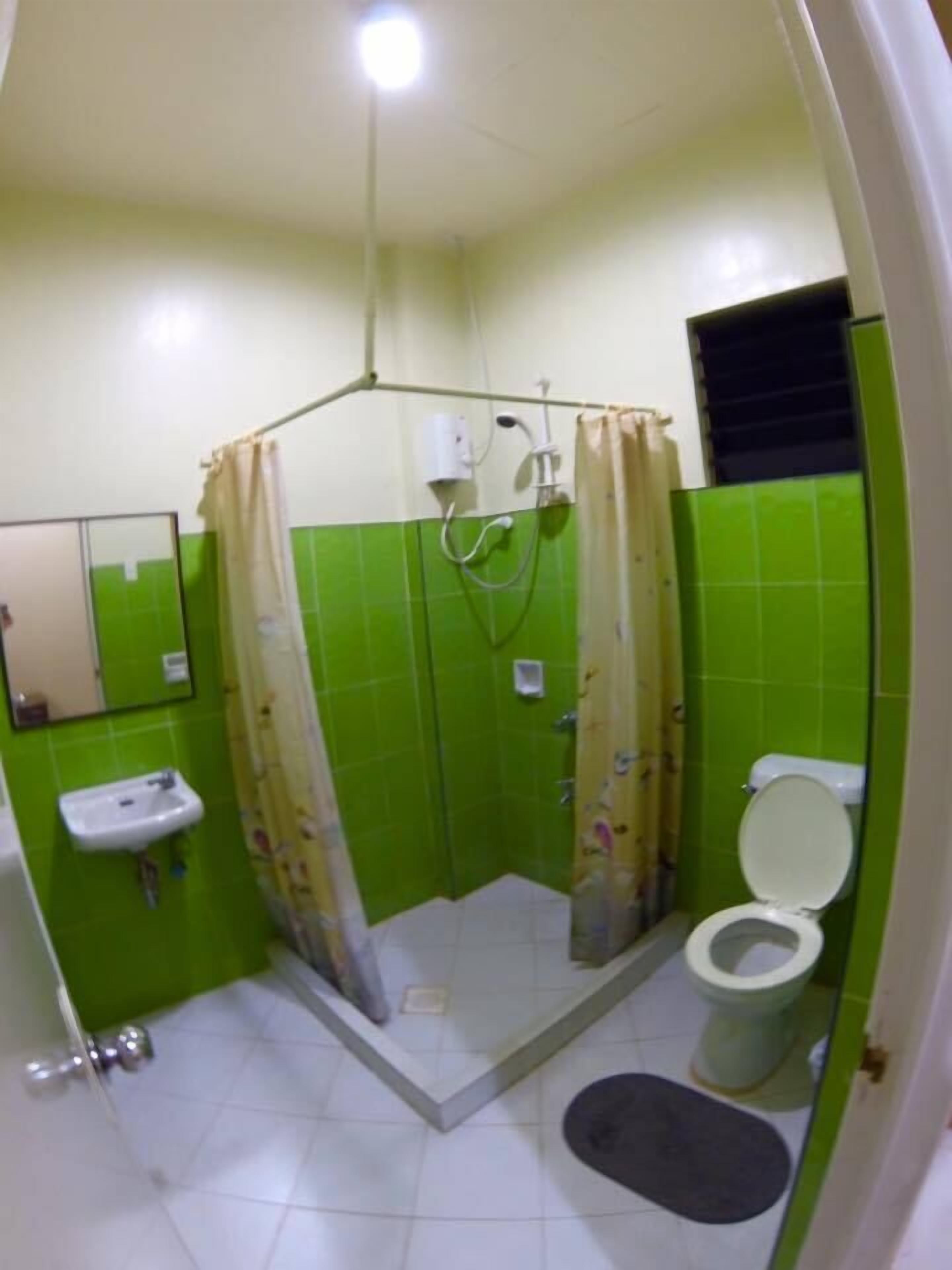 A bathroom with a shower, toilet, sink, and a mirror.
