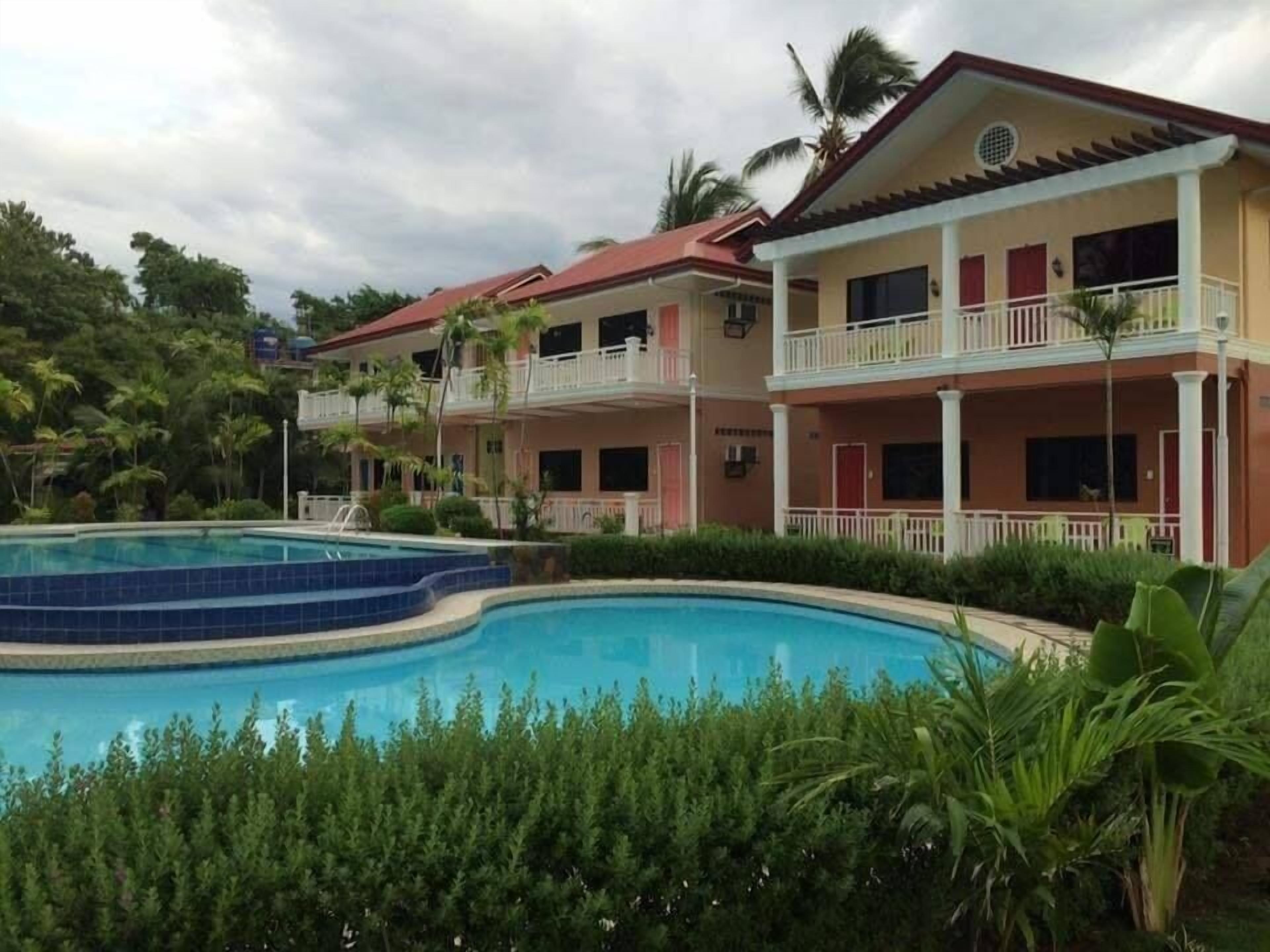 A hotel with a swimming pool, multiple balconies, and lush greenery.