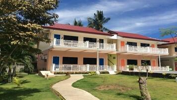 A two-story building with a red roof, balconies, and a paved walkway.