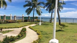A well-maintained garden with a paved pathway, palm trees, and a view of the ocean. - Northsky Beach Resort (Sogod)