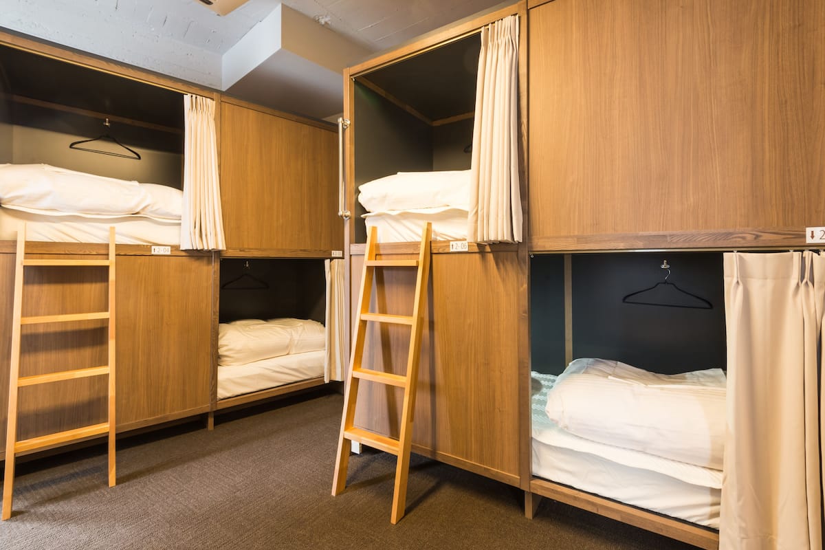 A dormitory room with bunk beds, wooden wardrobes, and a ladder.