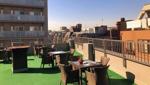 A rooftop terrace with outdoor seating, a view of the cityscape, and a building with multiple floors. - Tokyo Guest House Itabashijuku - Hostel (Tokyo)