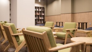 A library with wooden chairs and tables, bookshelves, and a ceiling with lights. - Tokyo Guest House Itabashijuku - Hostel (Tokyo)