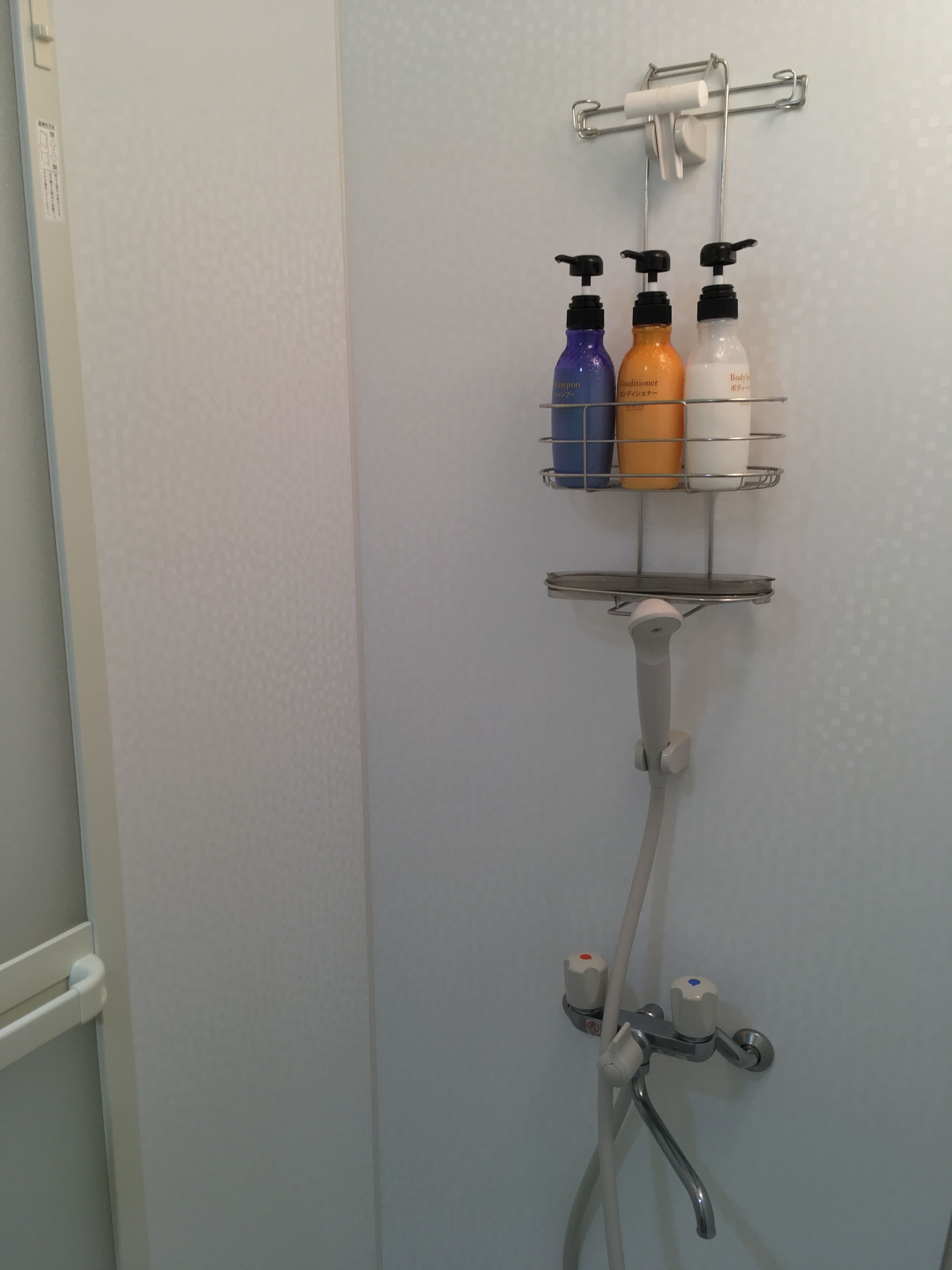 Une salle de bain équipée d’une douche, d’un porte-serviettes et d’une étagère pour ranger les articles de toilette.