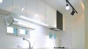 Una cucina moderna con mobili bianchi, un lavello in acciaio inossidabile e luci sotto i pensili.