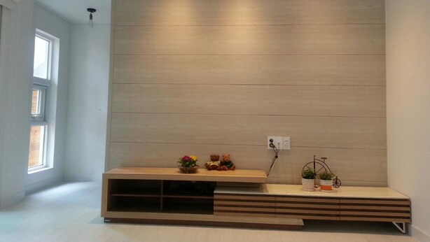 Un soggiorno moderno con una parete attrezzata in legno, una finestra e una piccola mensola con oggetti decorativi.