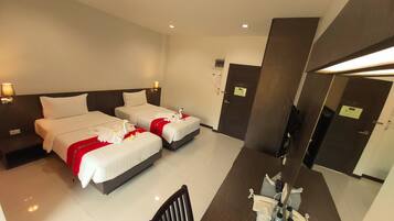 A hotel room with two beds, a desk with a chair, a mirror, and a bathroom door.