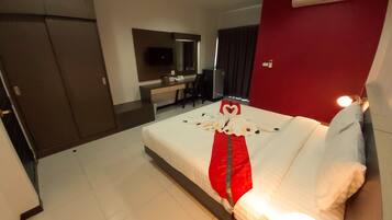 Une chambre d’hôtel avec un lit bien fait, un bureau avec une chaise, une télévision et un mur d’accent de couleur rouge.