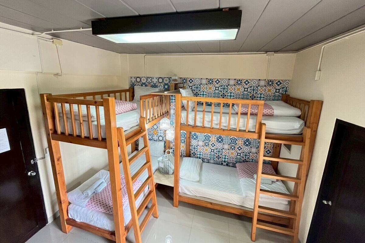 Un dormitorio con literas, pared de azulejos y una lámpara en el techo.