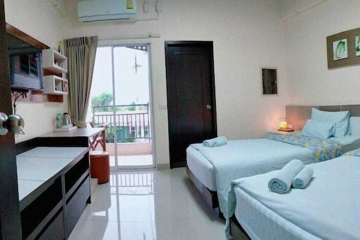 Habitación de hotel con dos camas, un escritorio, una silla, un armario y un balcón.