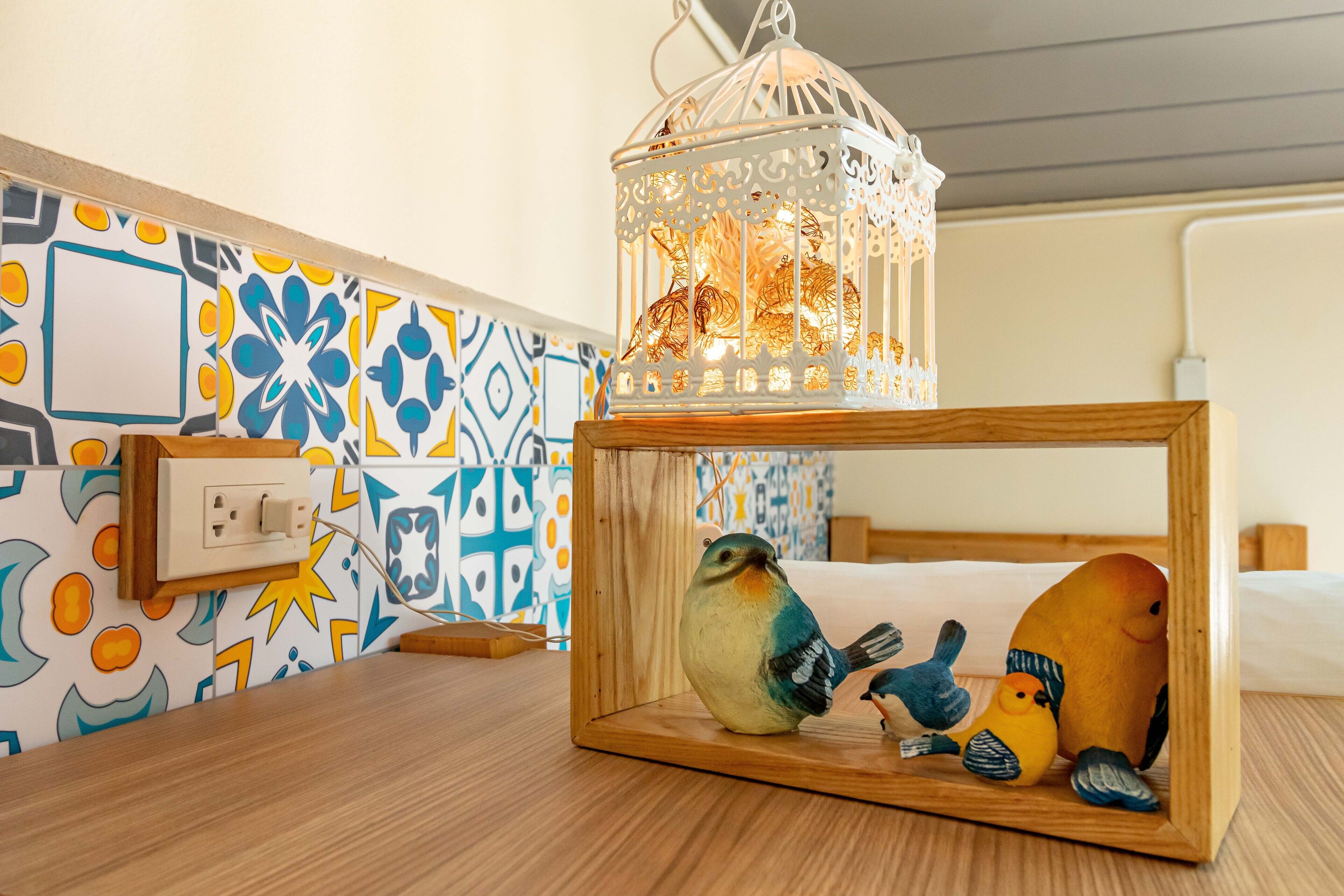 A wooden nightstand with a decorative bird figurine and a white lantern.