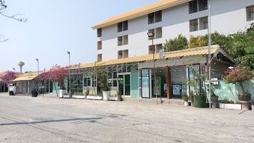A building with a flat roof, multiple windows, and a covered entrance area with potted plants.