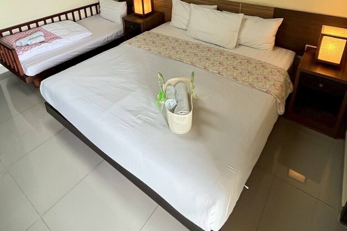 Habitación de hotel con dos camas, un adorno floral en la pared y una cesta pequeña con toallas en el suelo.