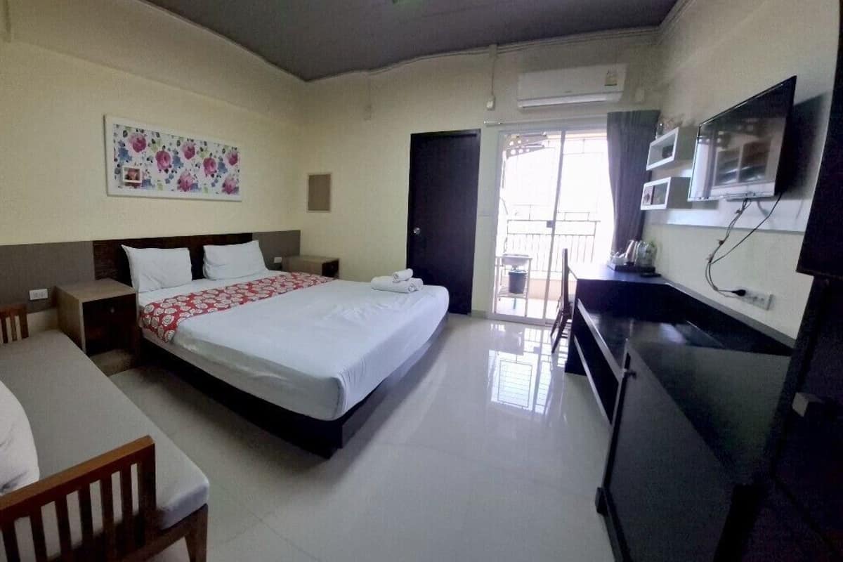 Habitación de hotel con cama, escritorio, televisión y balcón con vistas.