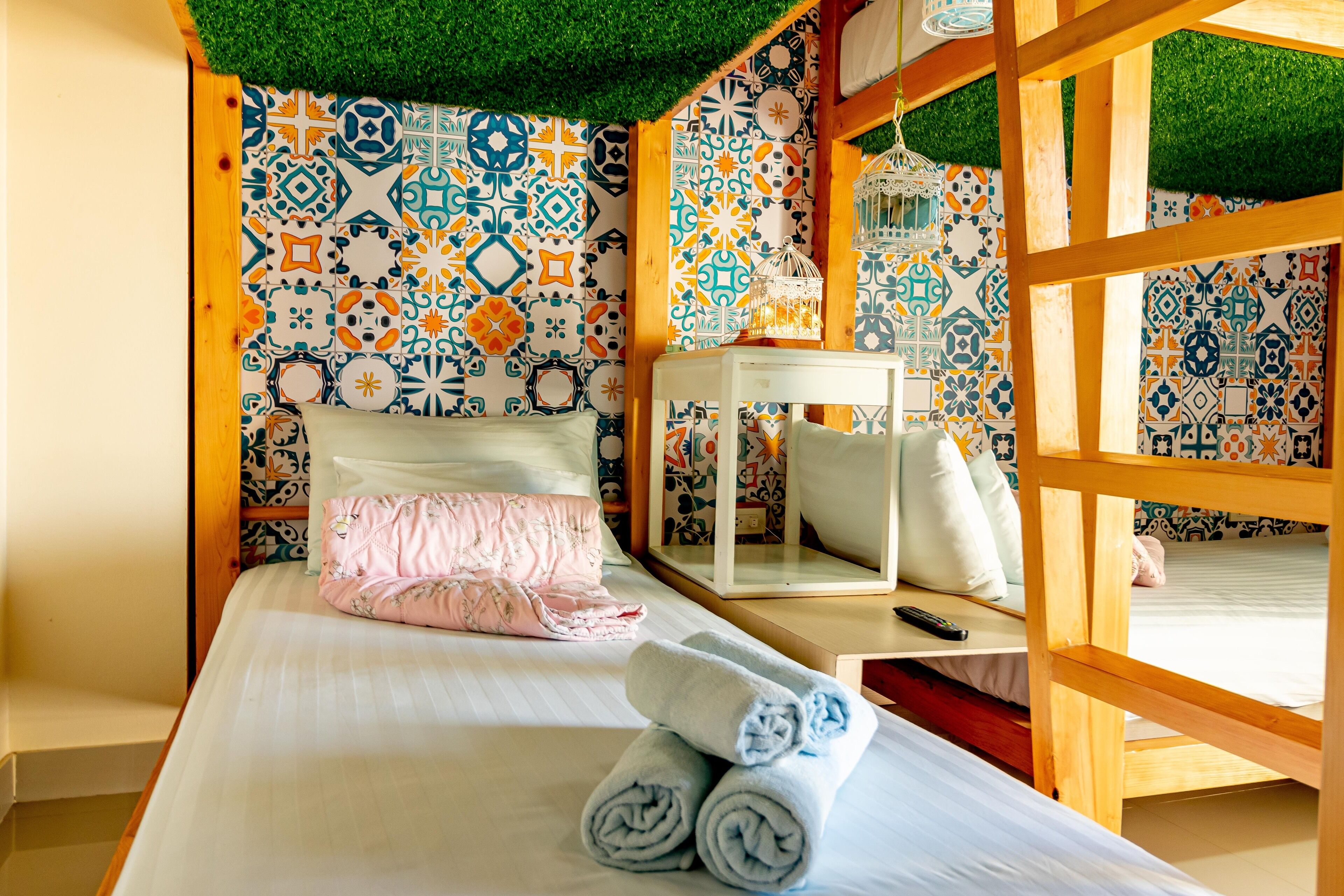 A room with a bed, a wooden bench, a mirror, and a wall with patterned tiles.