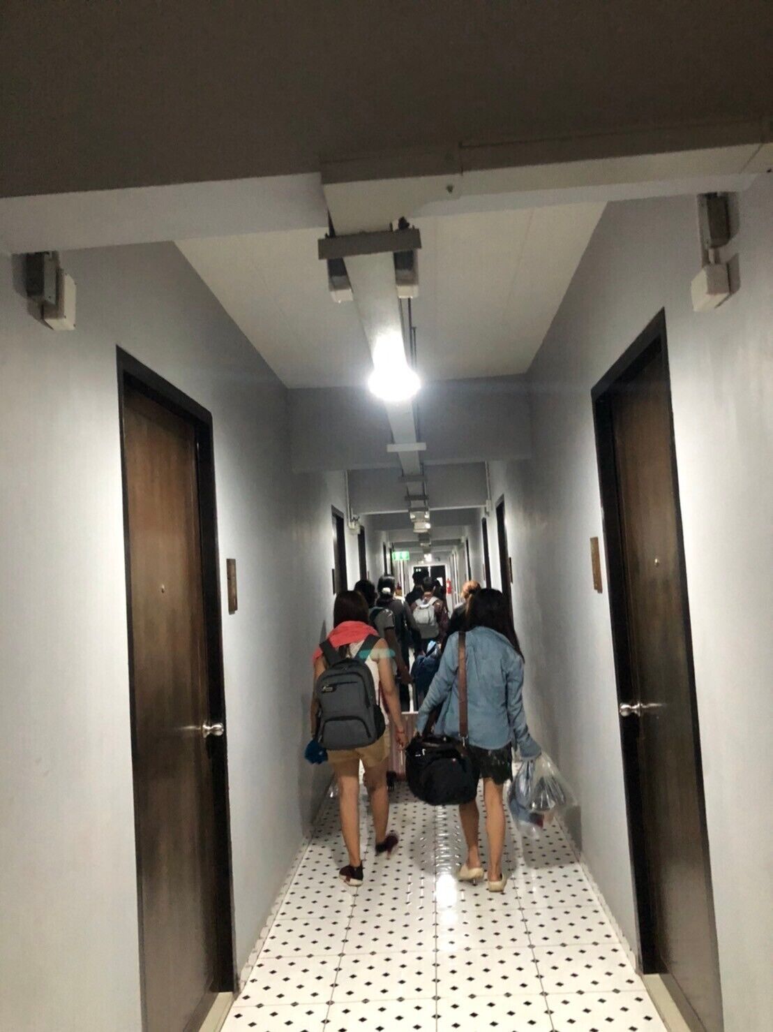 A narrow hallway with tiled flooring and doors on both sides.